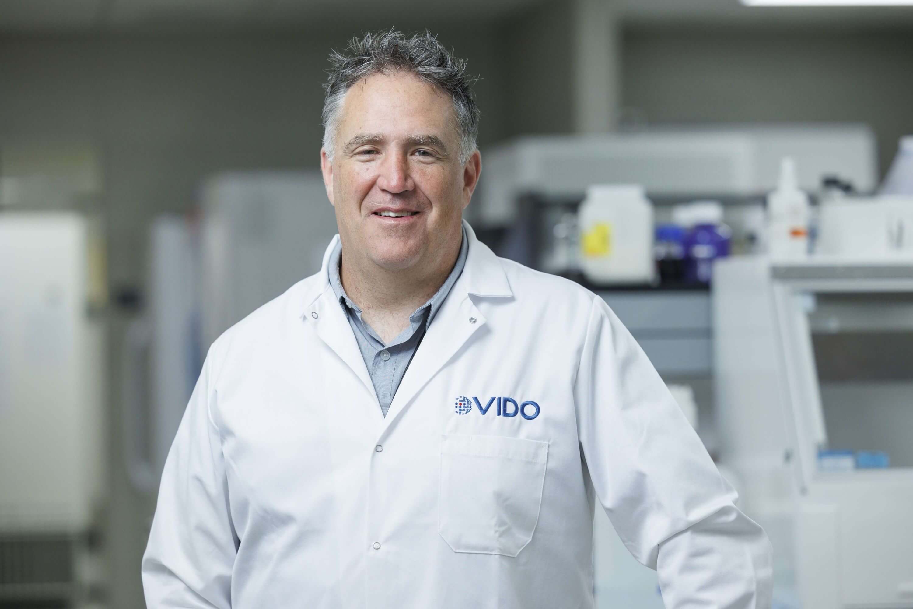 a male scientist in a lab coat looking at the camera