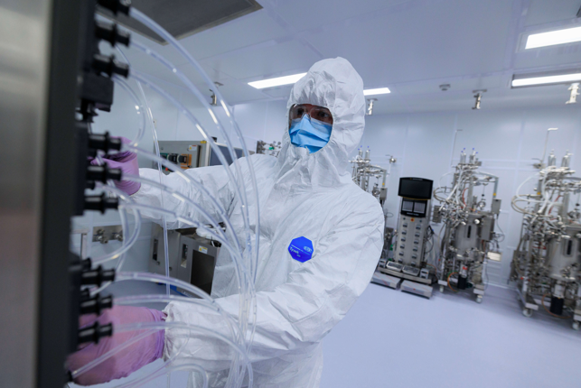 worker in PPE working with machines in lab