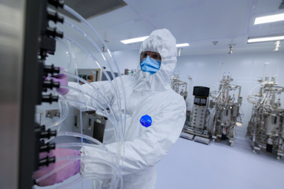 a technician in white PPE works on a machine